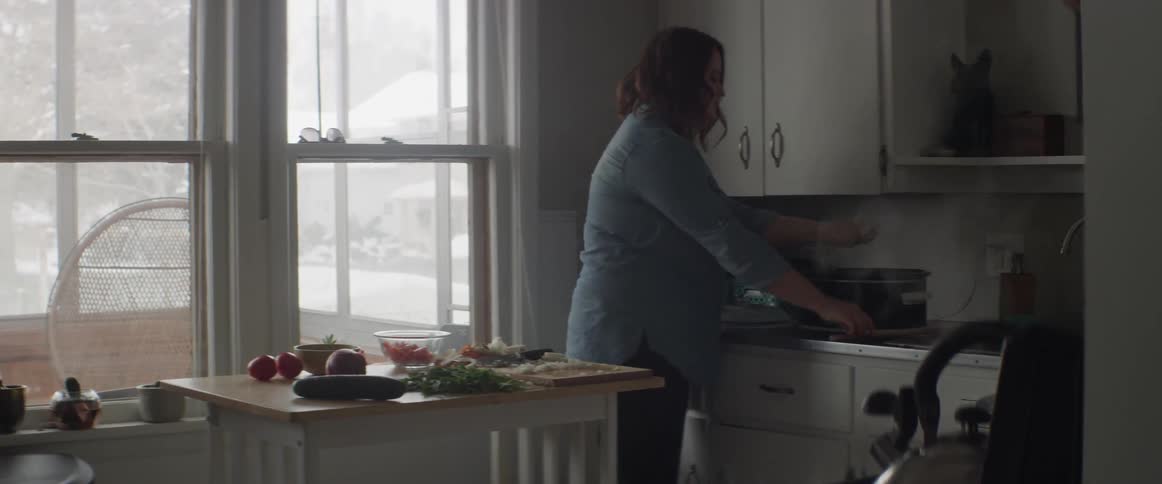 A woman is cooking putting ingredients in a pot