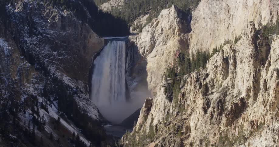 A waterfall gushes over a rocky cliff in the mountains