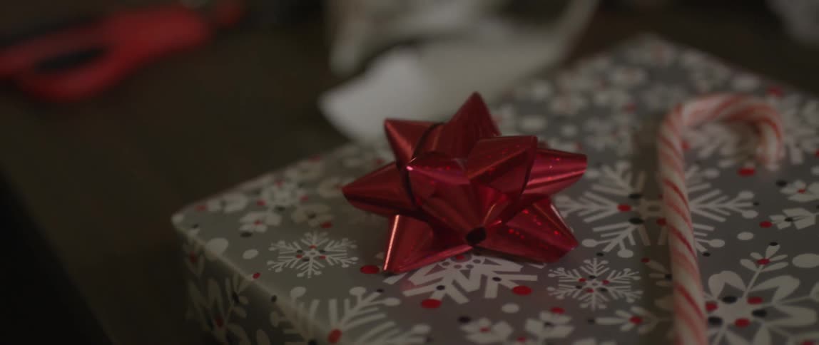A present is shown with a bow and a candy cane on top
