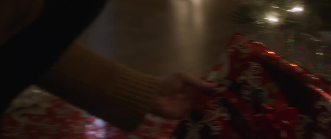 Person arranging christmas presents that are all wrapped in bright shiny paper