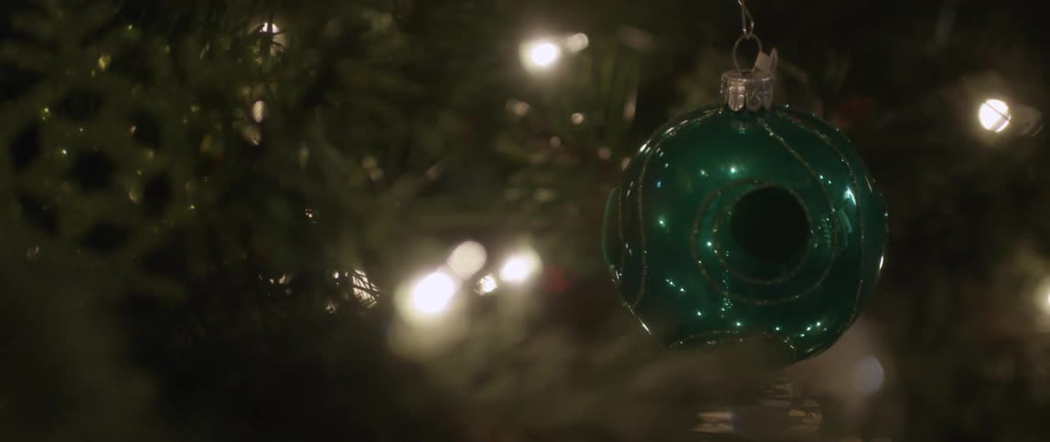 A green ball ornament hangs on a christmas tree