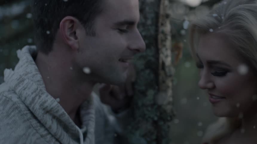 Man and woman smiling at each other as snow falls