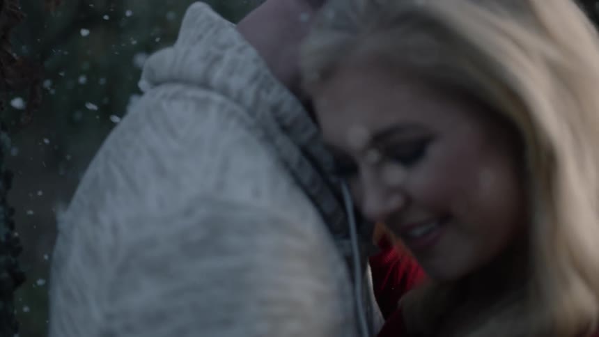 Woman puts her head on a mans shoulder as it snows around them
