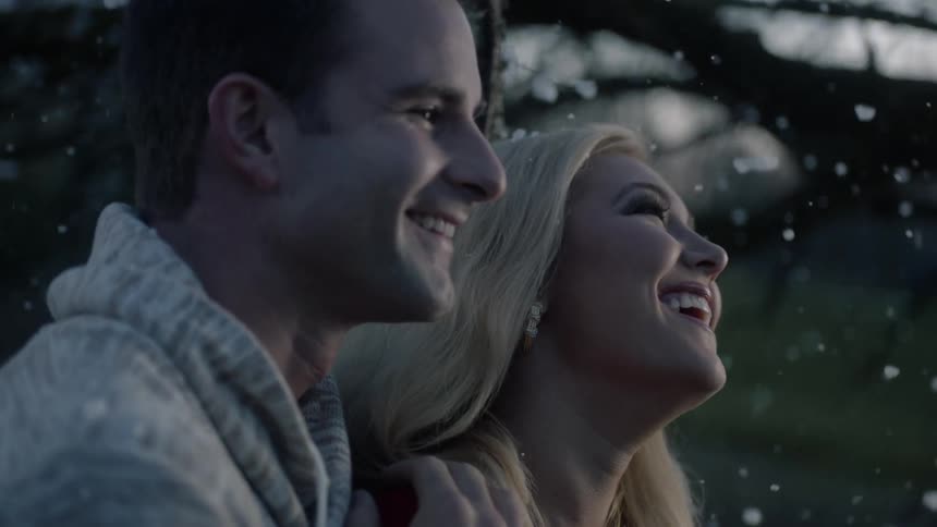 A man and woman embracing and laughing while it snows