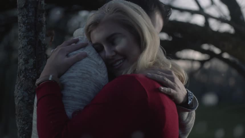Man and women talk before hugging as it snows