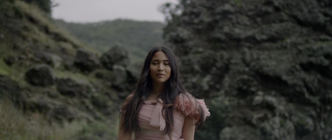 A woman smiles standing by some rocks