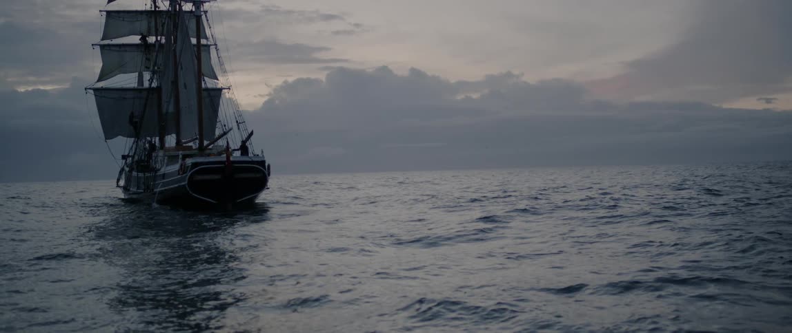 A sale boat is sitting in the middle of the ocean
