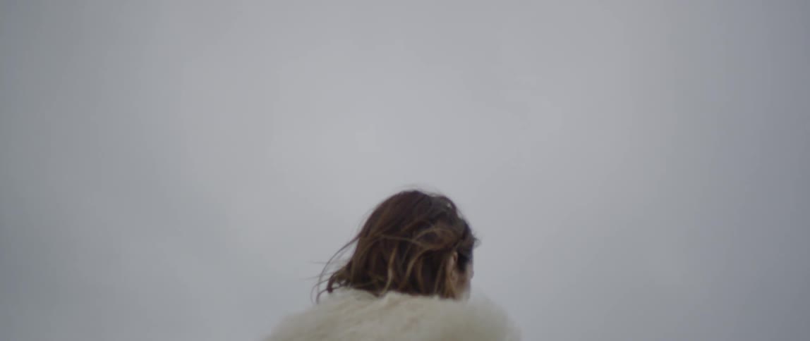 A woman wears a fur coat outside on a breezy day