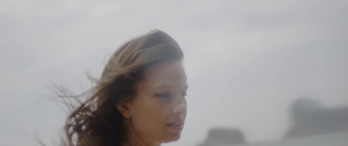 A woman walks on a beach on a windy day