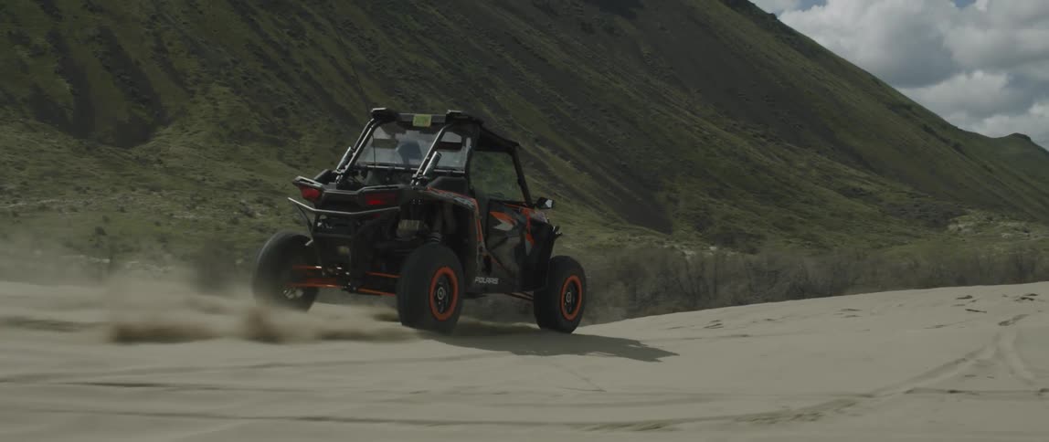 A dune buggy races over the sands during the day