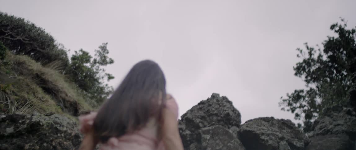 A woman climbs up the rocks on a cloudy day