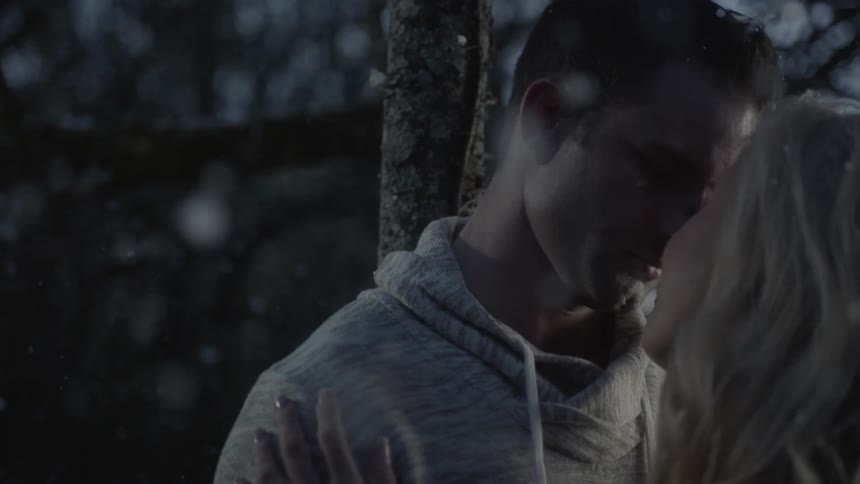Man kisses a woman as it snows