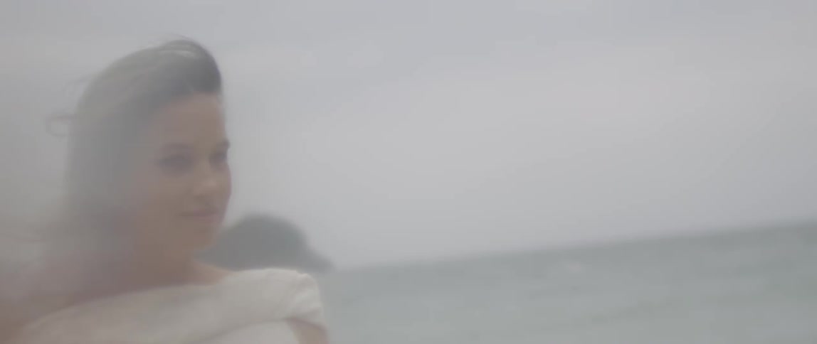 Woman stands outside near water on a windy day
