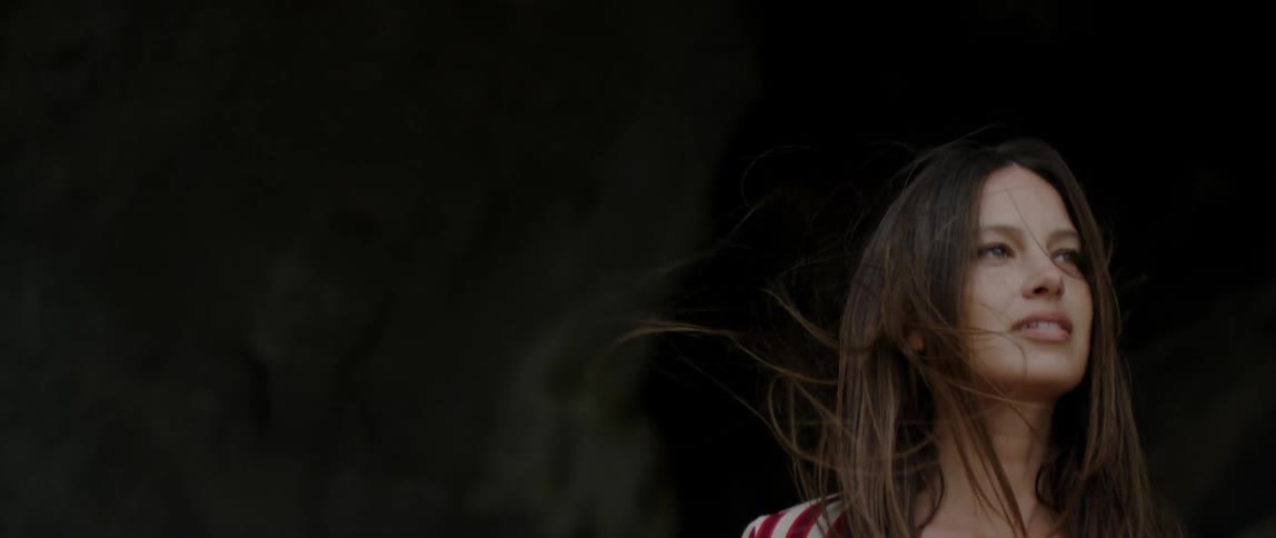A woman is walking through a cave on a windy day