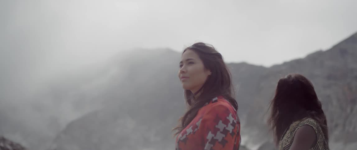 Two women walk hand in hand near the mountains