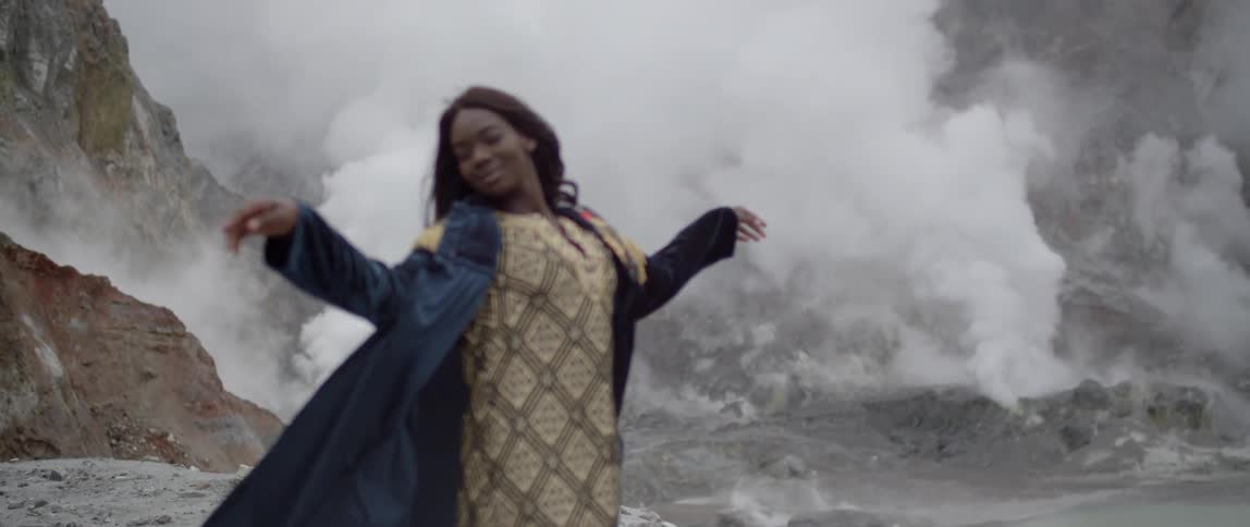 A woman is standing on the edge of a volcano