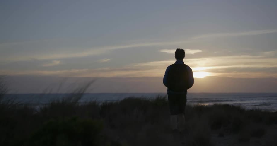 A man hikes towards the water on a windy day