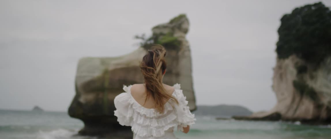 A woman in a white dress runs on the beach