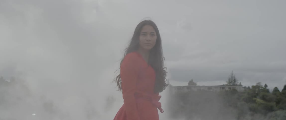 Woman wearing a red dress walks outside with steam surrounding her