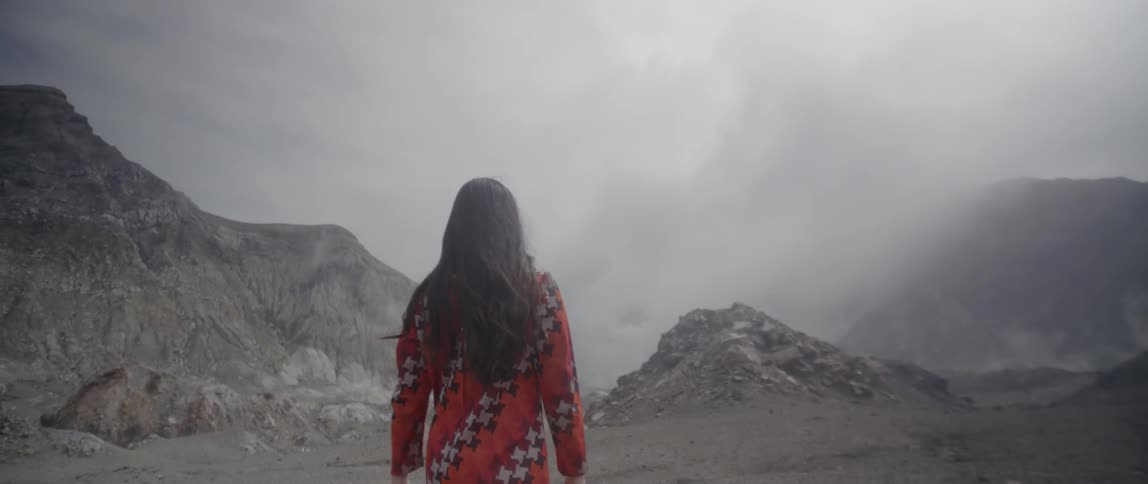 A woman walks in the mountains on an overcast day