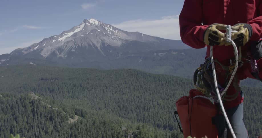A rock climber fastens his rope on a mountain
