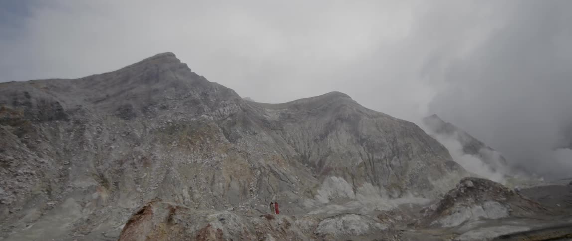Hikers stand at the base of a rocky mountain
