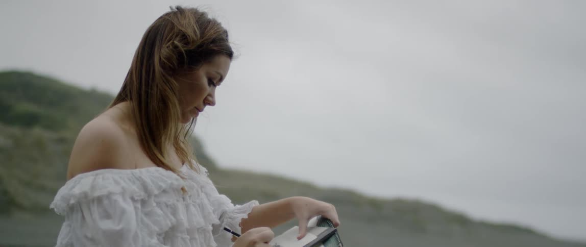 A woman writes on paper outdoors