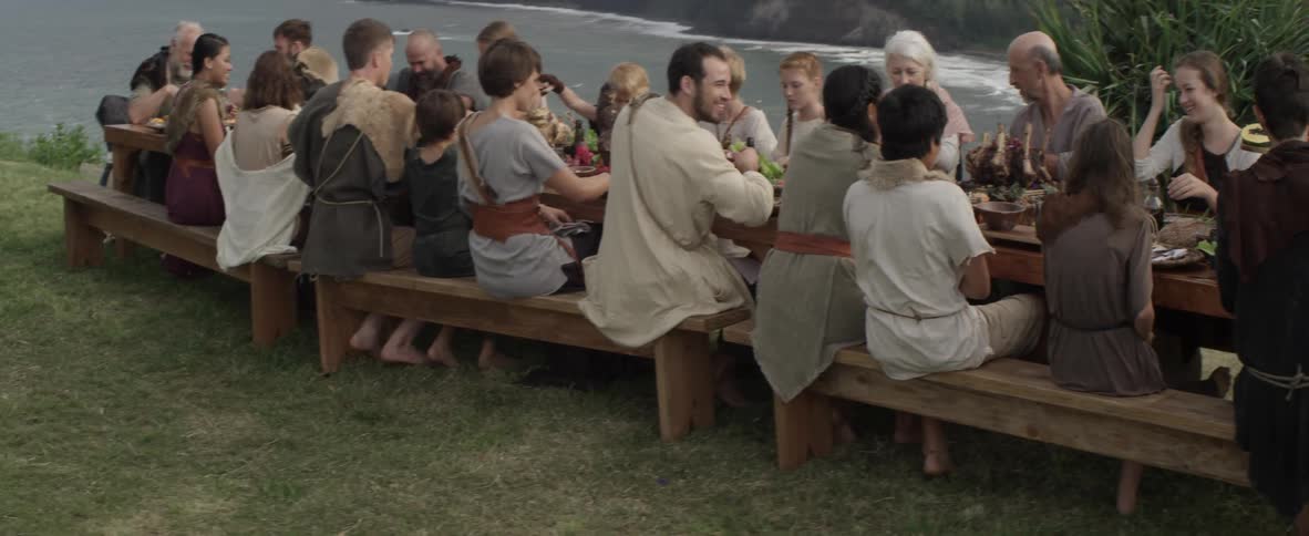 A family dines at an outdoor table on the coast