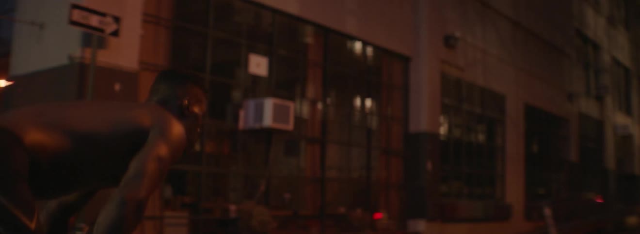 Shirtless man bends over and looks at a building
