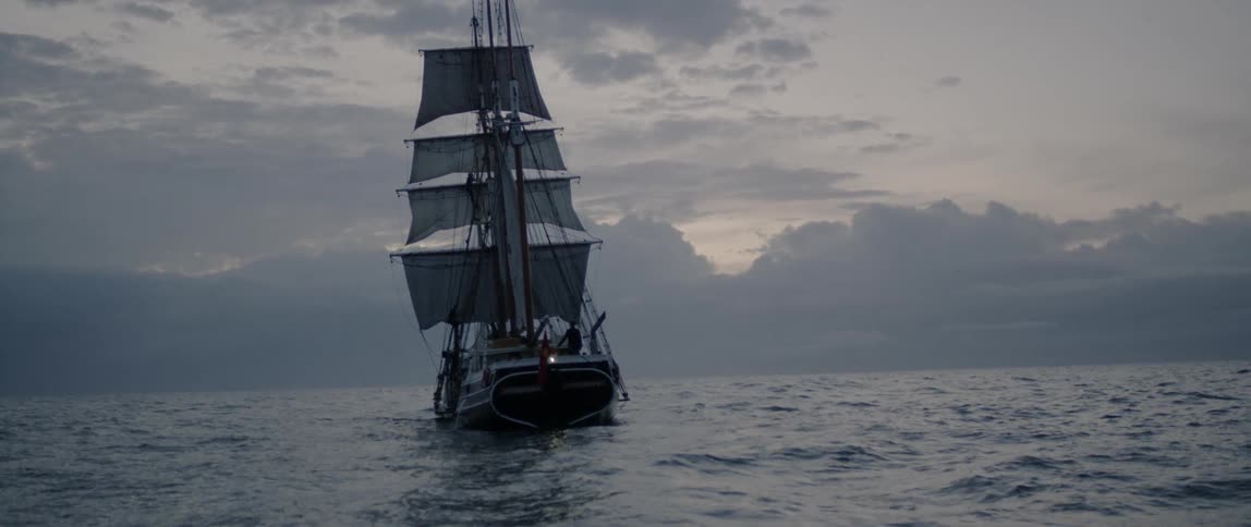 A ship floats on the ocean at sunset