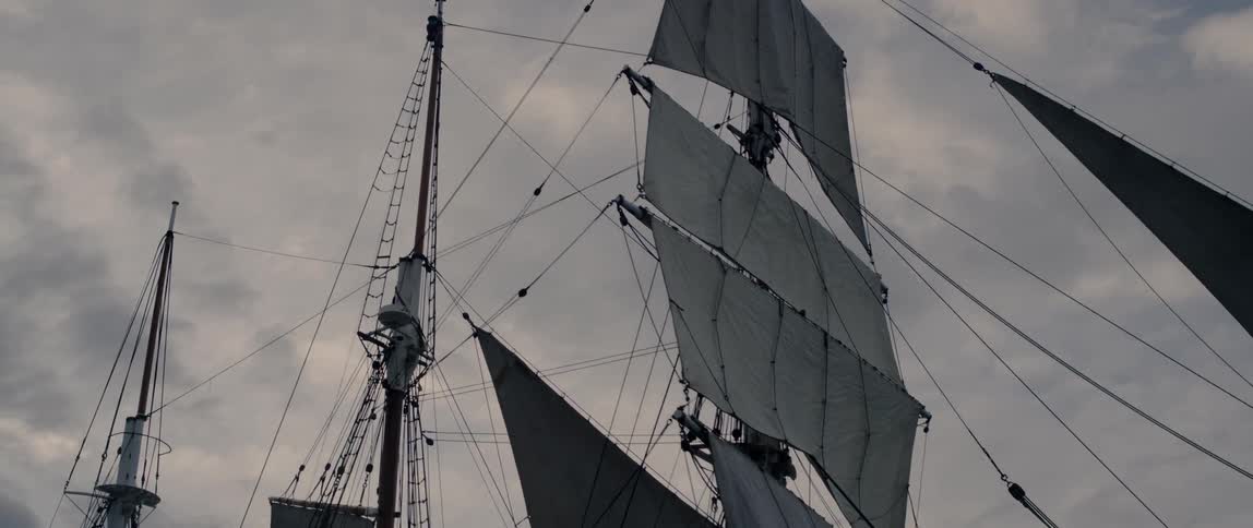 Ship sails are shown on a cloudy day