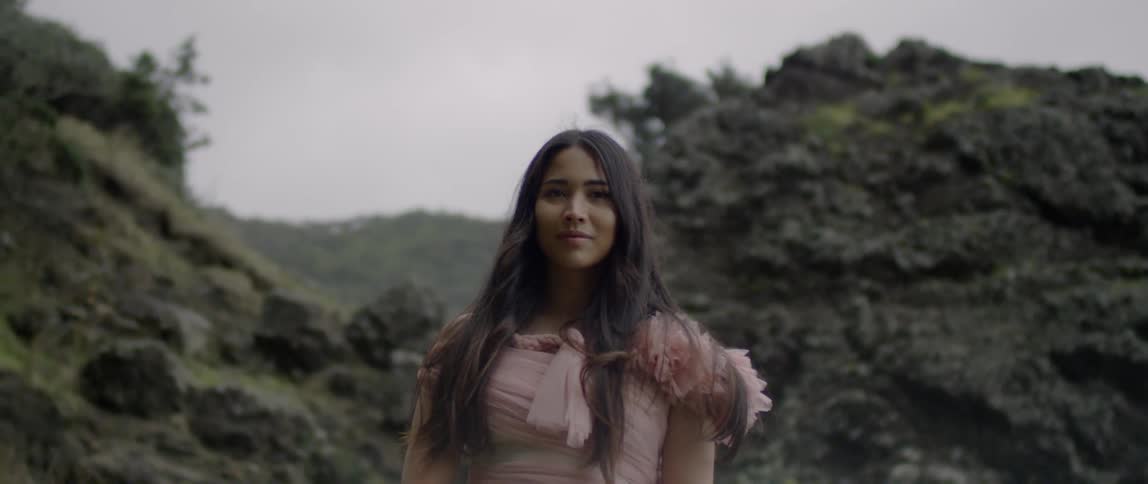A woman is standing near some hills smiling