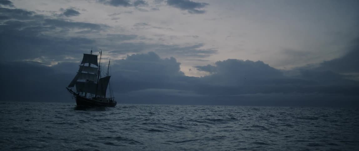 A boat sails in the water at sunset