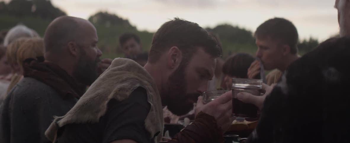 A family sits at a table outside eating and drinking