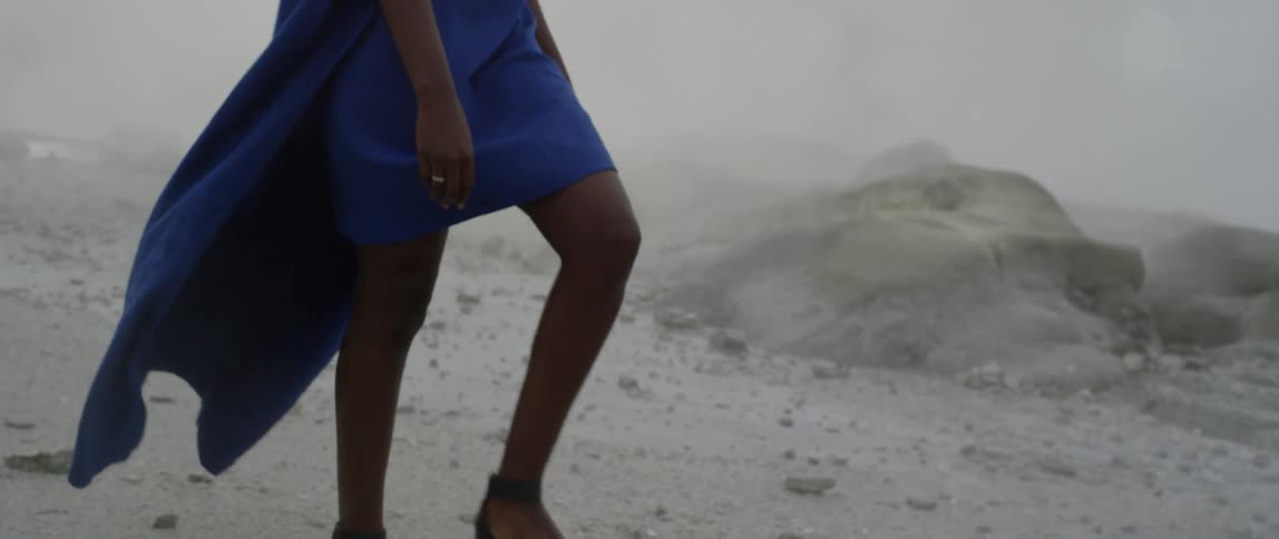 A woman walks across snowy ground on a foggy day