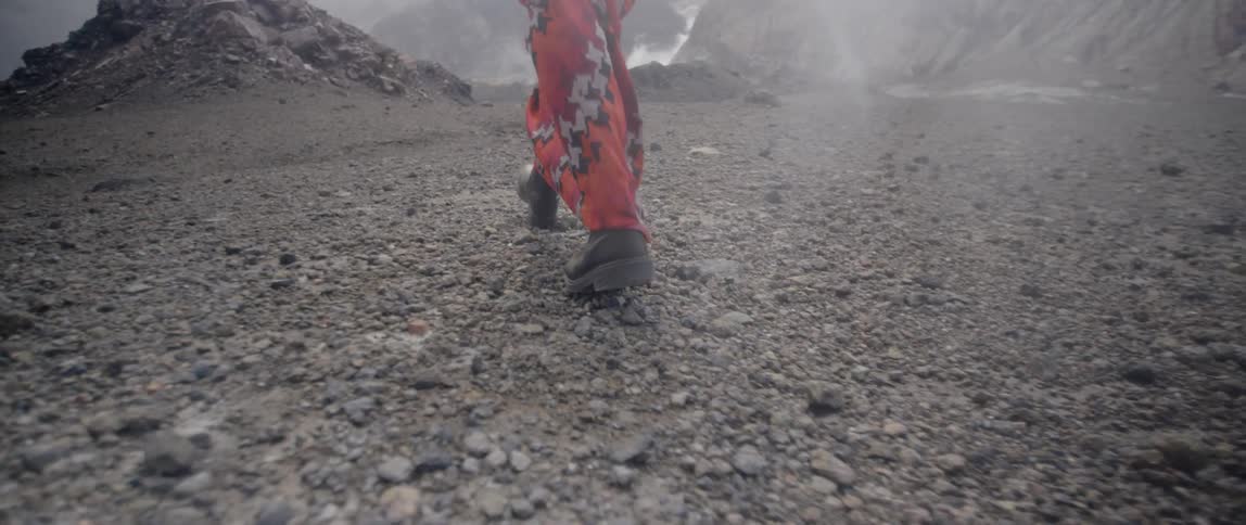 A person in red walks along the rocks
