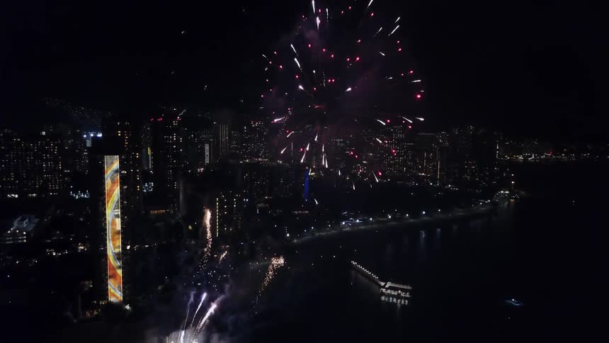 Fireworks light up the sky over a city and river