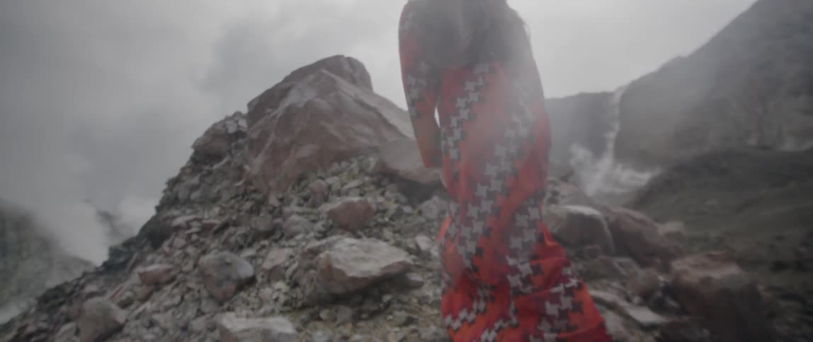 Woman wearing a long dress walks up a rocky hill