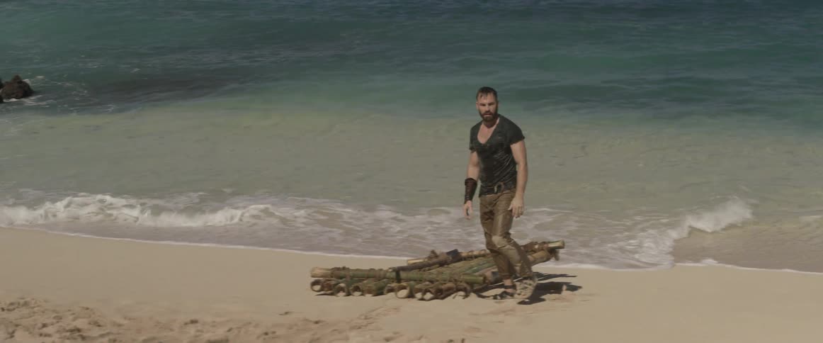 A man gets up off the sand and stares down something