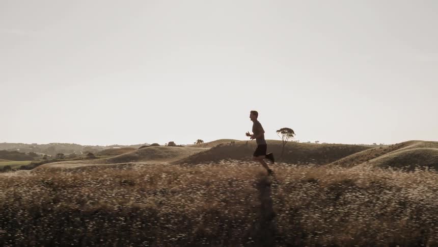 A man jogs along a hilltop during the day