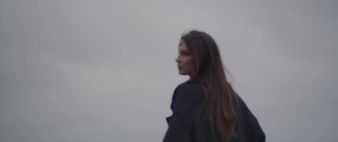 A woman looks at the ocean on a cloudy day