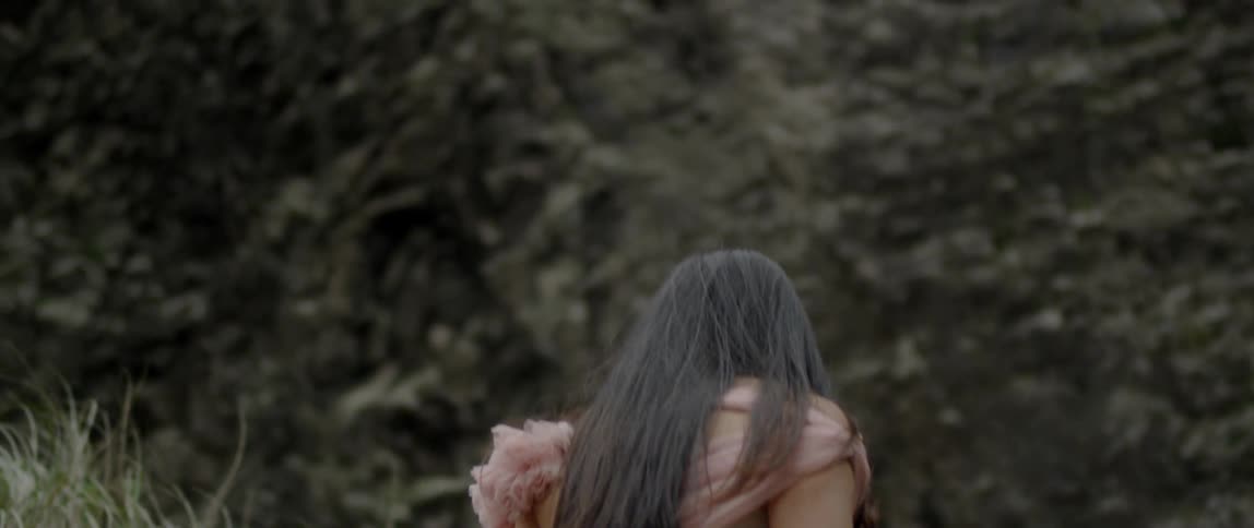 A woman walks through the wilderness towards a mountain