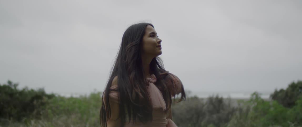 A woman turns as she looks around on a cloudy day