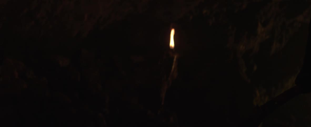 A person is walking through a dimly lit cave