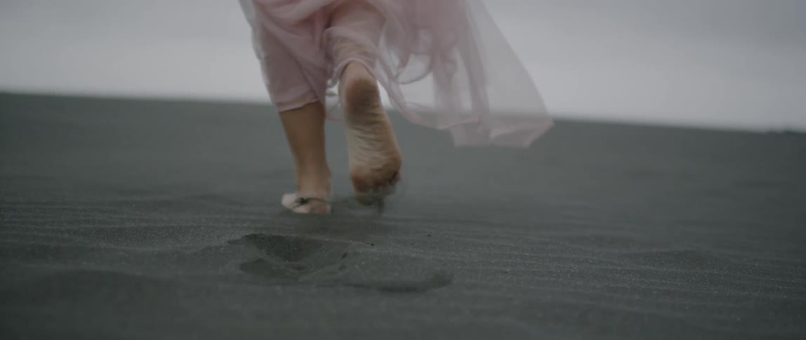A woman leaves footprints on a sandy beach