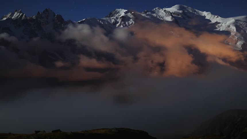 Clouds roll over snowy mountain tops