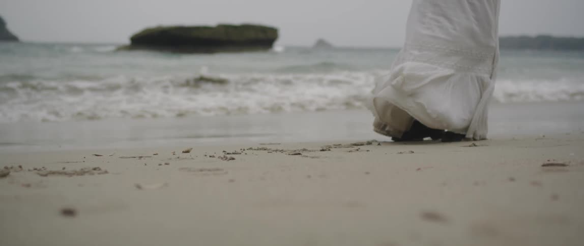 A woman in  white dress stands on the beach