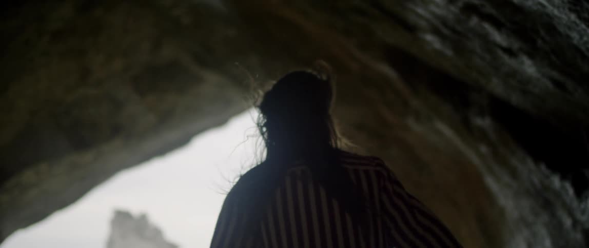 A woman walks through a windy cave