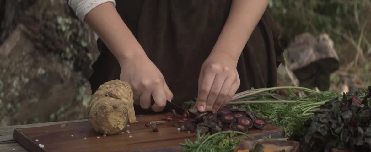 A girl is cutting vegetables on an outdoor table