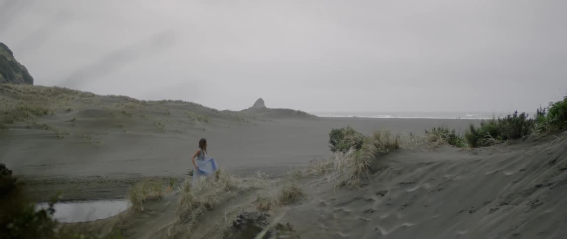 A woman walks on a sandy beach